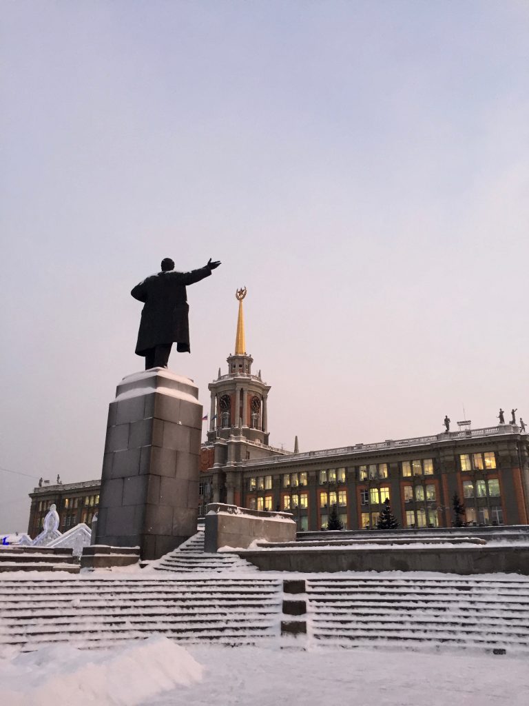 A statue of Lenin stands opposite of Yekaterinburg's city administration building that is topped with a red Soviet star.