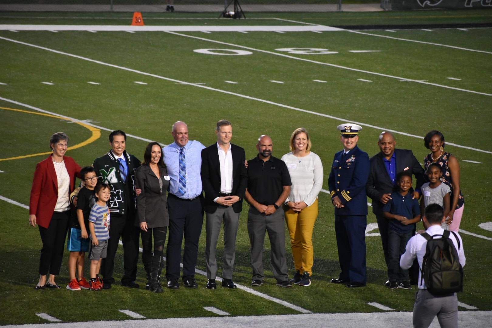 Abdullah and his family on a football field receiving an award alongside other families. 